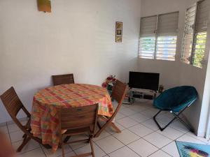 a room with a table and chairs and a television at Residence Corail in Sainte-Rose