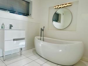 ein weißes Bad mit einer Badewanne und einem Spiegel in der Unterkunft Verbier Luxurious Seaside Retreat in Aberdyfi + 24 Fotos