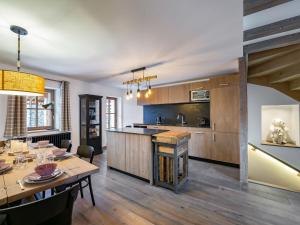 a kitchen with wooden cabinets and a table and a dining room at Chalet moderne avec parking et wifi, à proximité des pistes et commerces - FR-1-566-20 in Les Allues