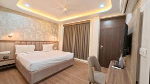 a bedroom with a bed and a desk and a television at Hotel Ravindraya Residency in Varanasi