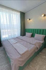 a large bed with a green headboard in a bedroom at Стрийська Автовокзал Арена Львів in Lviv