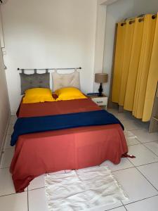a bedroom with a bed with colorful sheets and yellow pillows at villa Rony in Port-Louis