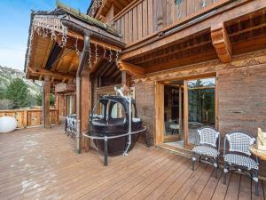 una terraza de madera con sillas y una mesa en una casa en Chalet 5⭐ à Méribel avec Spa, Salle de Sport, Proche des Pistes et Commerces - FR-1-566-62, en Les Allues