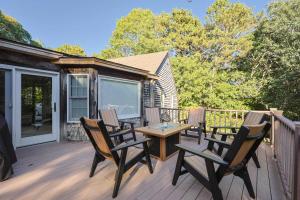 une terrasse avec quatre chaises et une table en bois dans l'établissement Stay On The Cape Vacation Rentals Cape Cod Getaway Near Beaches & Bike Trail, à Eastham