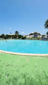 ein großer Pool mit blauem Wasser mit Gebäuden im Hintergrund in der Unterkunft Studio les pieds dans l'eau belle vue mer in Le Gosier