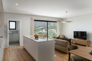 a white kitchen and living room with a couch at Saraiva Hills II Relaxation in Câmara de Lobos in Panasqueira +21 photos