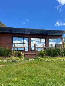 a house with large windows on a green lawn at Cabana Romântica em Pelotas in Pelotas