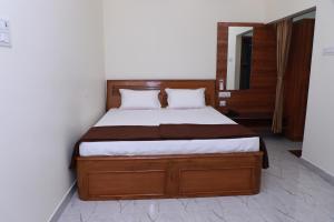 a bedroom with a bed with a wooden bed frame at Temple View Residency in Tiruvallūr