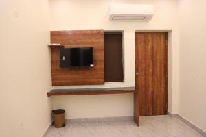 a room with a flat screen tv on a wall at Temple View Residency in Tiruvallūr