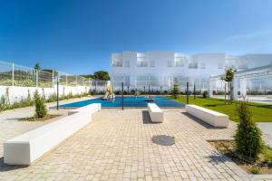 a courtyard with two white benches in front of a building at Lujoso chalet con jardín privado a 300 metros de la playa in Conil de la Frontera