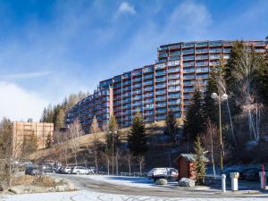 a large building on a hill with cars parked in a parking lot at Appartement lumineux 60m² · 2 ch. · Balcon · WIFI · Parking - FR-1-346-557 in Arc 1800