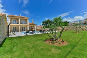 a house with a tree in the yard at Luxury Stone Villa BANOVI with heated pool in Vinjerac