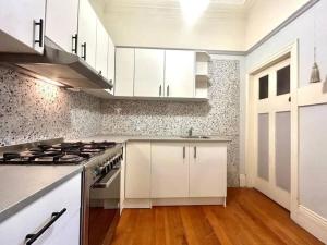 a kitchen with white cabinets and a stove top oven at Haberfield House in Sydney