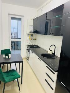 a kitchen with a sink and a table with a green chair at RxM HOME CITY in Chiajna