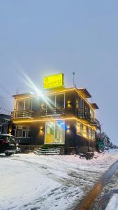 a building in the snow with the sun shining on it at Glampfire Hotel and Cafe in Jispa