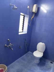 a blue bathroom with a toilet and a window at Morni Home's morjim in Morjim