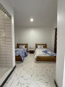 a bedroom with two beds and a tile floor at Mlangoni Cottages in Sanya Juu