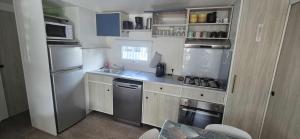 a small kitchen with stainless steel appliances and cabinets at mobile home camping la pignade in La Tremblade