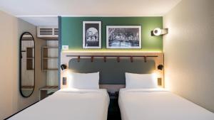 two beds in a room with green walls at Campanile NATURE - Colmar Parc des Exposition in Colmar