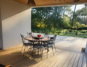 a table and chairs on a deck with a view of a yard at Villa Kentève in Parentis-en-Born