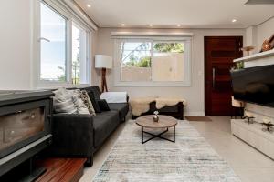a living room with a black couch and a tv at Casa Paris em condomínio até 8 p in Canela