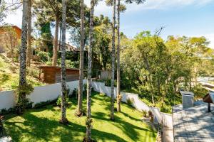 a backyard with palm trees and a fence at Casa Paris em condomínio até 8 p in Canela