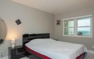 a white bedroom with a bed and a window at Oceanfront Two Bedroom Condo with Panoramic Views in Neptune Beach