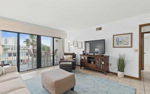 un salon avec une télévision, un canapé et des chaises dans l'établissement Oceanfront Two Bedroom Condo with Balcony and Heated Pool, à Cocoa Beach