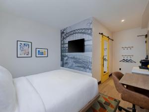 a bedroom with a bed and a desk and a tv at voco Astoria by IHG in New York