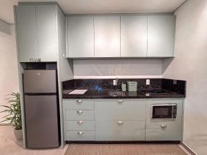 a kitchen with white cabinets and a refrigerator at Flat Completo c/ Piscina e Garagem in Brusque