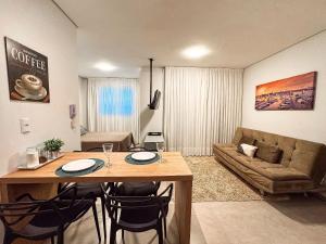 a living room with a table and a couch at Flat Completo c/ Piscina e Garagem in Brusque
