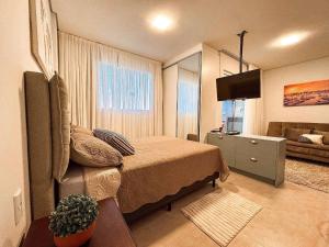 a bedroom with a bed and a television in it at Flat Completo c/ Piscina e Garagem in Brusque
