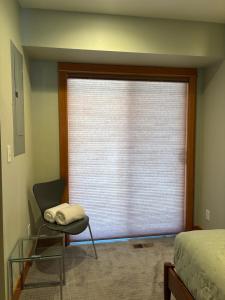 ein Fenster mit Jalousie in einem Schlafzimmer mit einem Stuhl in der Unterkunft B2 Townhome with BBQ on the Deck in Hood River