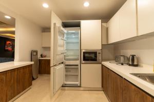 ラホールにあるGold Crest Presidential Family Apartments-DHA Lahore Phase 4の白いキャビネットと冷蔵庫のあるキッチン