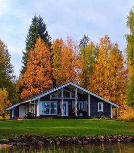 a black house with autumn trees in the background at Willa Mäntyniemi in Impiö