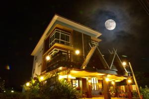 Una casa con luna llena en el cielo en หมื่นช้างน่านบูทีคHotel, en Nan