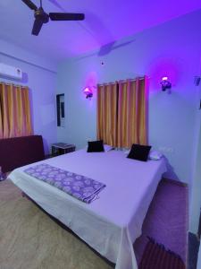 a bedroom with a large white bed with purple sheets at Shree Datt Yatri Niwas Akkalkot in Solapur
