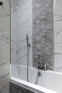 a bath tub with a shower and a sink at Flatzy - 3 Bedroom Apartment in Heart of City Centre in Liverpool +24 photos