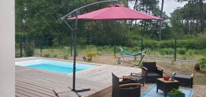 a red umbrella sitting on a deck next to a pool at Villa Kentève in Parentis-en-Born