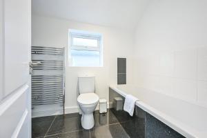 a white bathroom with a toilet and a bath tub at The Grove by Tŷ SA in Cardiff