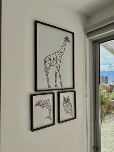 a group of four framed drawings of a giraffe on a wall at Comfy Loft near El Tesoro MDE OSLO in El Poblado