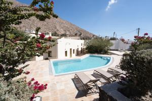 a swimming pool with chairs and a building at Mantilida Villa in Emporio Santorini