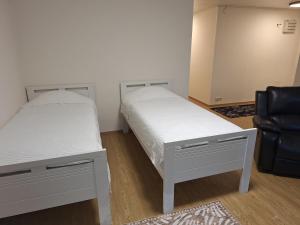 a bedroom with two beds and a black chair at Mäntsälä Centrum- huoneisto saunalla ja ilmaisella pysäköinnillä in Mäntsälä
