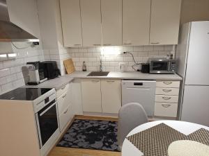a small kitchen with white cabinets and a microwave at Mäntsälä Centrum- huoneisto saunalla ja ilmaisella pysäköinnillä in Mäntsälä