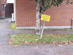 a yellow sign sitting in front of a tree at Mäntsälä Centrum- huoneisto saunalla ja ilmaisella pysäköinnillä in Mäntsälä
