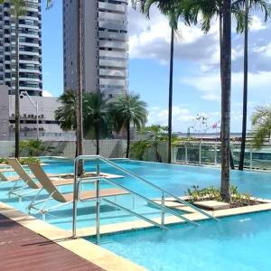a swimming pool with palm trees and a building at Ap 2 Quartos na Doca em Prédio de Luxo in Belém
