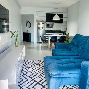 a living room with a blue couch and a kitchen at Ap 2 Quartos na Doca em Prédio de Luxo in Belém