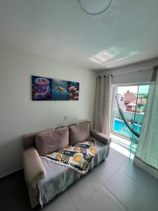 a bedroom with a couch and a window with a view at Refúgio Azul de Maragogi in Maragogi