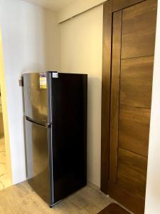 a stainless steel refrigerator next to a wooden door at Modern and Cozy 3BR Staycation Home in Tarlac