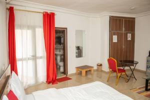 a bedroom with red curtains and a bed and a table at Hotel Etoile De Kennedy in Bouaké